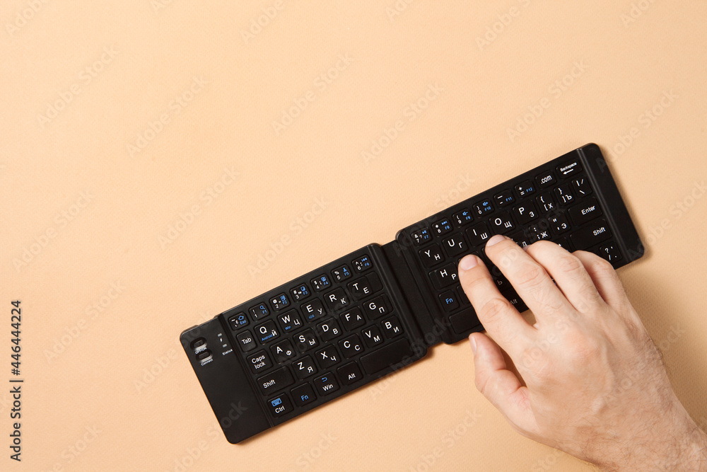 A man hand typing with wireless keyboard on the brown background A man hand typing with wireless keyboard on the brown background