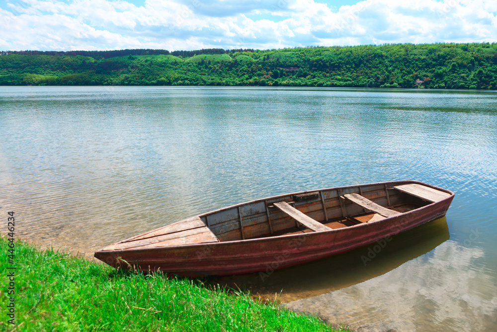 Wooden boat moored at the green shore