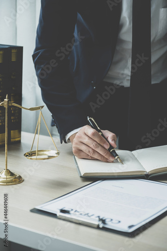 Lawyer hand holding pen and providing legal consult business dispute service at the office with justice scale and gavel hammer