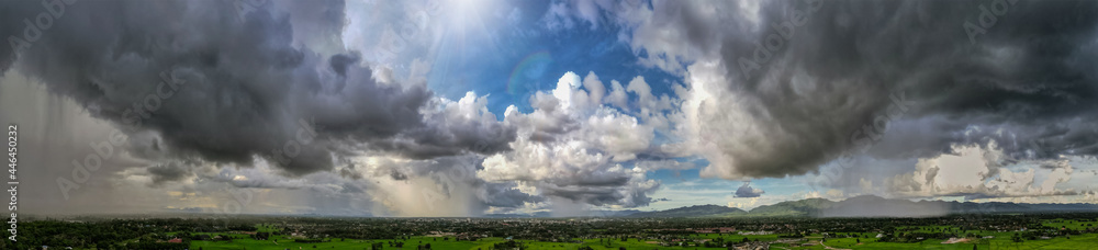 Panorama of the cloudy gray sky with storm running over a town in a valley in back of a mountain covered, Dark sky dramatic black cloud before the rain. rainy storm over rice fields, Thailand Panorama of the cloudy gray sky with storm running over a town in a valley in back of a mountain covered, Dark sky dramatic black cloud before the rain. rainy storm over rice fields, Thailand