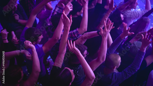 Music Festival Goers Party with Their Hands Up in the Air at a Concert in a Night Club. Shot from Above with Fans Cheering a Rock or Indie Band. Bright Colorful Strobing Lights Makes the Atmosphere photo