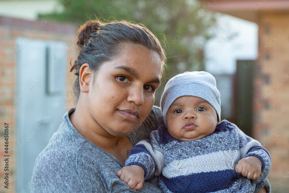 Attractive young mother holding her baby outside