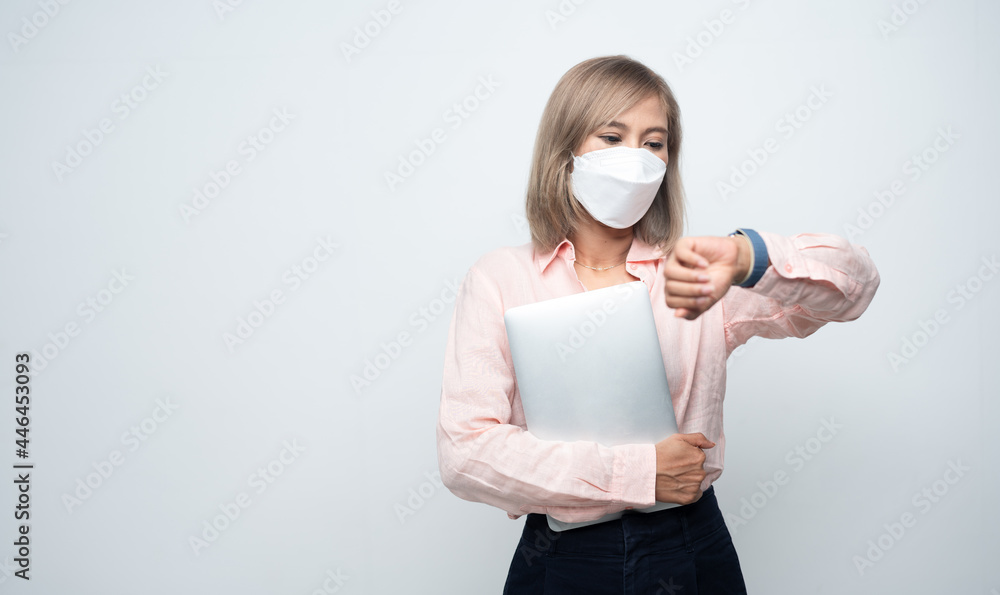 Portrait of young office woman wearing medical face mask for protection in covid-19.Holding laptop on her hands and checking time for meeting. Portrait of young office woman wearing medical face mask for protection in covid-19.Holding laptop on her hands and checking time for meeting.