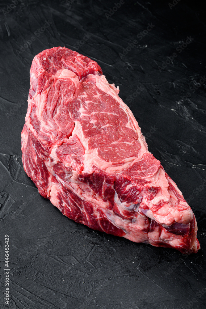 Raw Marble beef black Angus, ribeye or scotch fillet, on black stone background