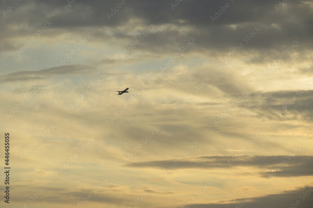 Airplane in yellow sky at sunset, natural background 