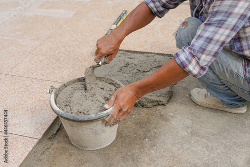 worker scooping mixed mortar in a bucket to tiled on the floor,selective focus
