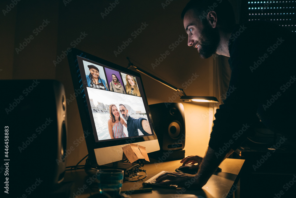 Fototapeta premium Young man indoor at home having videocall using computer smiling having fun
