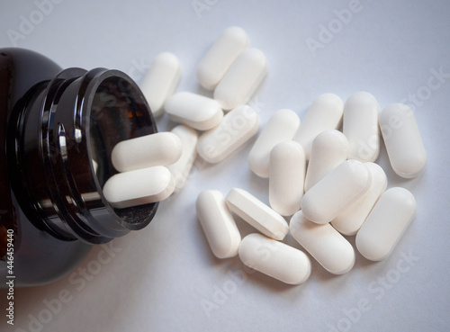 Tableau sur toile White medicinal pills are scattered from a brown bottle container close-up