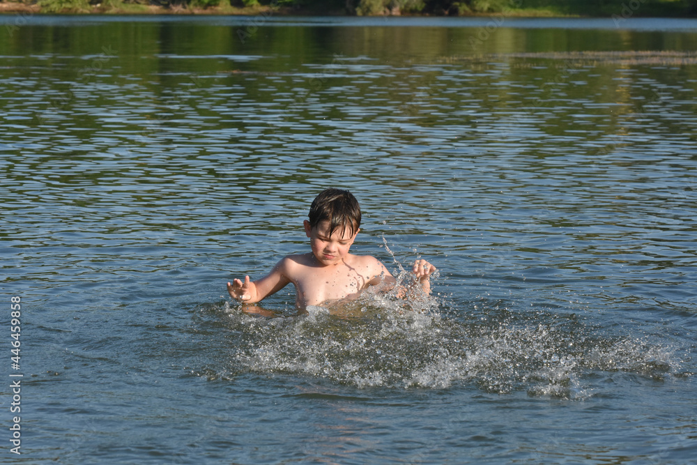 Child playing and swimming in the water. Boy splashing in a water on hot sunny day