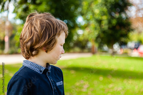 profile of unsure young autistic boy looking to the side at a park outside photo