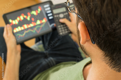 Young man holding a tablet and investing in the global stock market. Trading concept.
