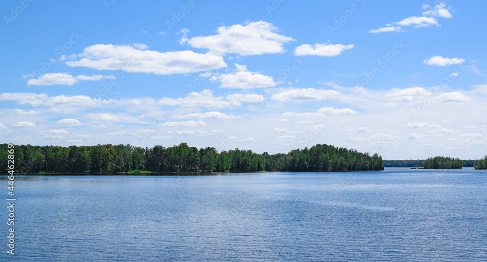 Beautiful summer landscape. Bright blue sky, white clouds, lake, forest.