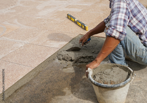 worker with trowel and mixed mortar in a bucket to tiled on the floor,selective focus