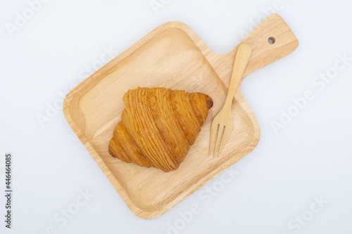 Croissant on wooden plate isolated on white background.