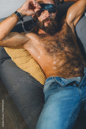 Portrait of a brutal bearded man with a naked torso.