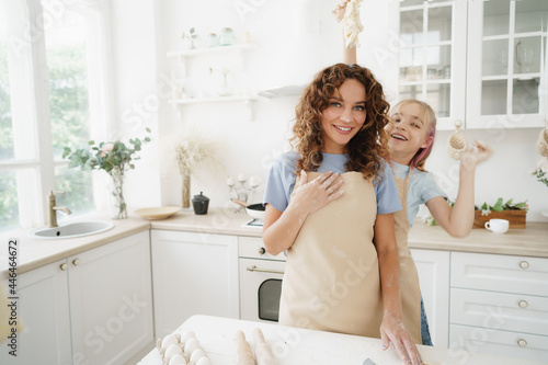 Mother and daughter having fun while cooking dough in kitchen