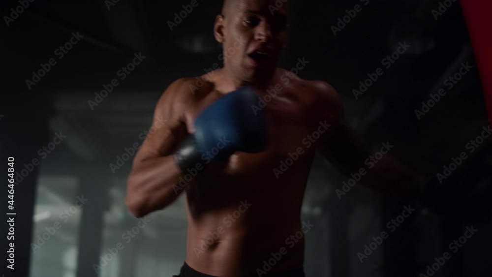 Man doing boxing training in loft building. Male fighter kicking punch bag Man doing boxing training in loft building. Male fighter kicking punch bag
