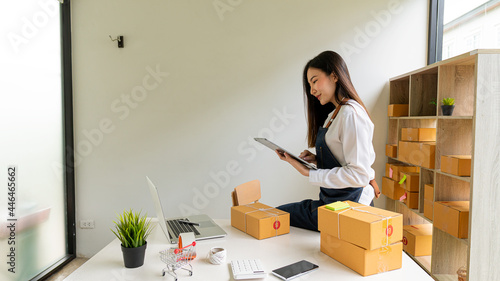 Start a business smeA beautiful Asian businesswoman works with boxes and laptops to take orders from customers and enjoys working from home online selling ideas and delivery. photo