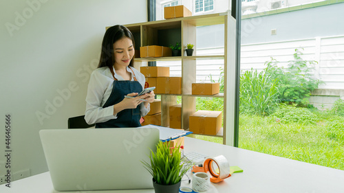 Start a business smeA beautiful Asian businesswoman works with boxes and laptops to take orders from customers and enjoys working from home online selling ideas and delivery. photo