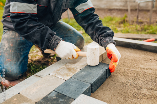Foto Fitting and tamping paving stones with a rubber mallet - installation of paving