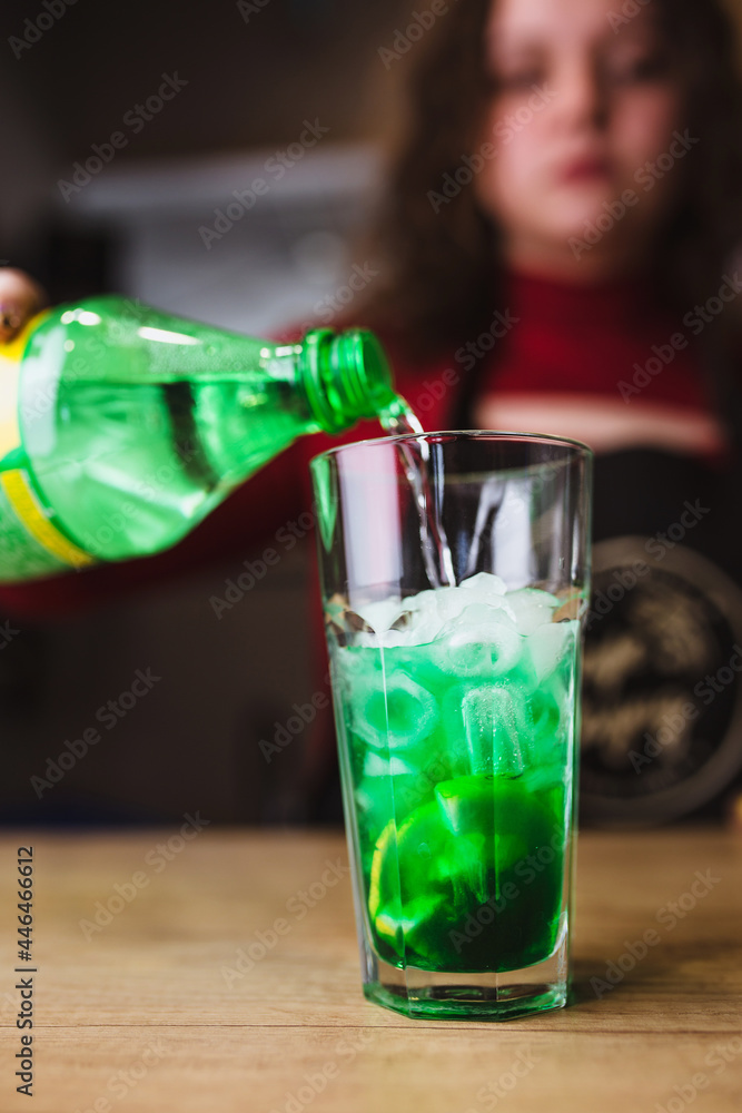 Φωτογραφία Sweet lemonade with lemon and ice cubes in a glass - the girl makes a green cock