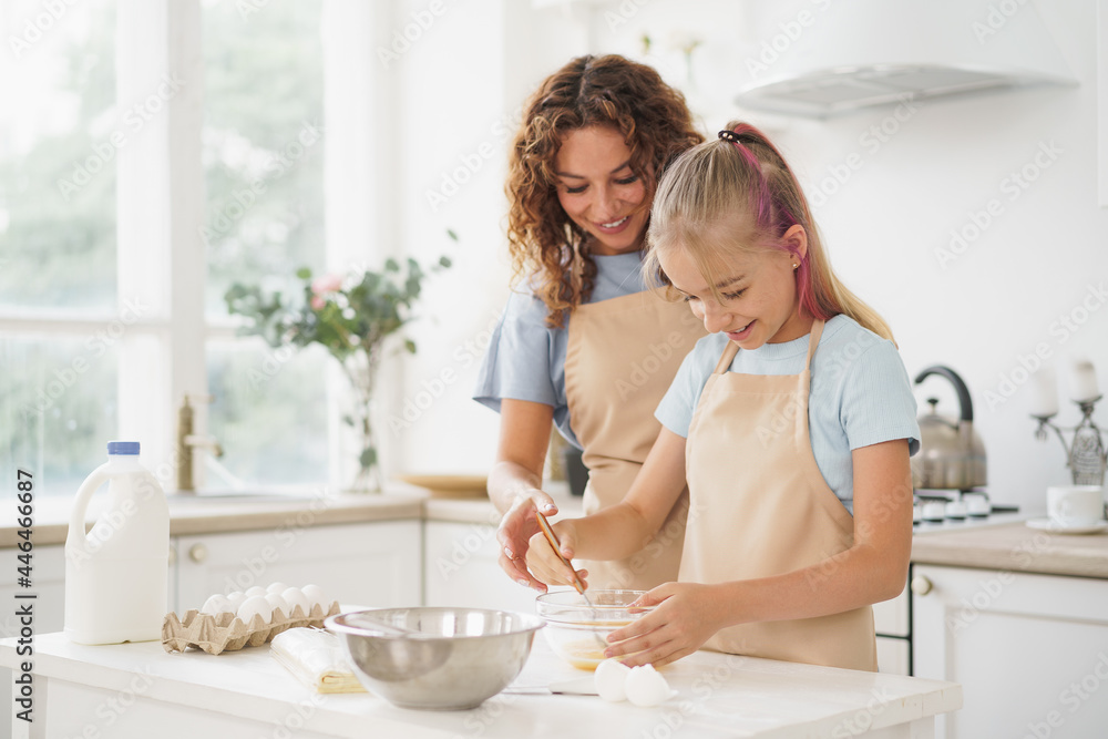 Mother and teen daughter making dough for pastry toghether in kitchen Mother and teen daughter making dough for pastry toghether in kitchen