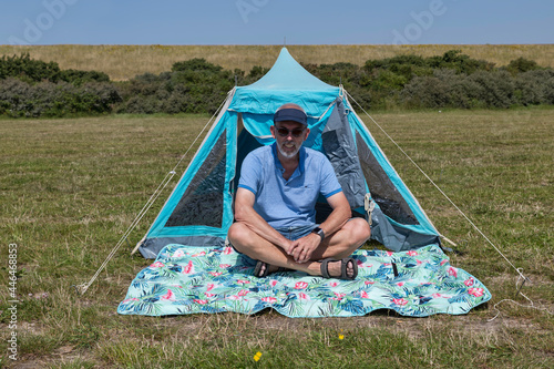adult man sitting in front of a tent