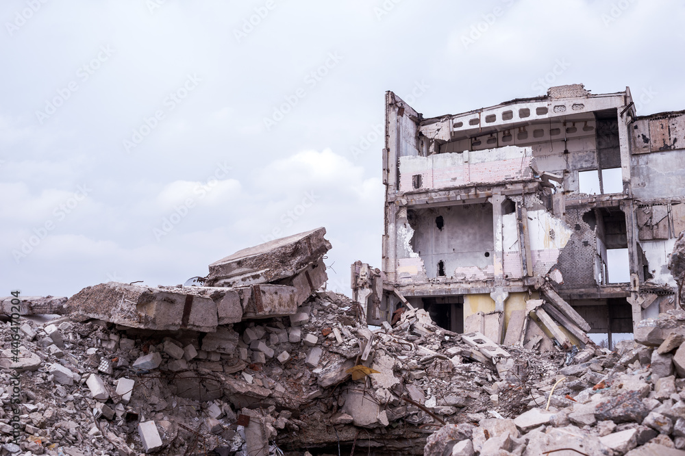A destroyed building against a gray sky with a pile of concrete rubble in the foreground. Background A destroyed building against a gray sky with a pile of concrete rubble in the foreground. Background