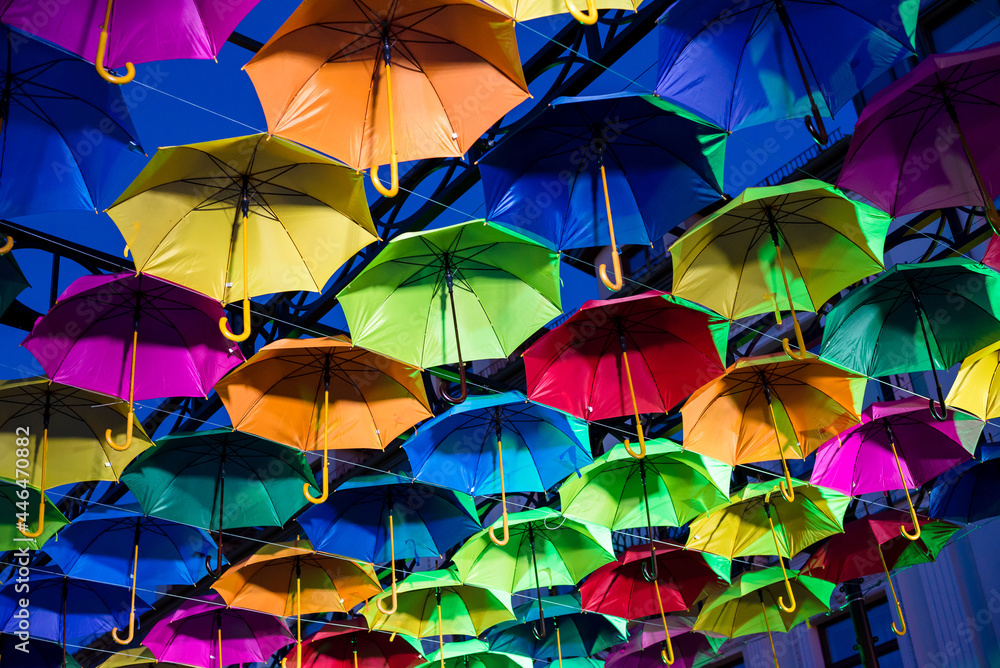 Obraz premium Colorful umbrellas in the evening. Colorful umbrellas in the sky. Street decoration from umbrellas. Background of umbrellas. 