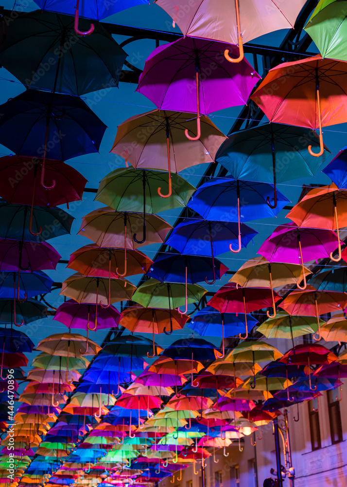 Obraz premium Colorful umbrellas in the evening. Colorful umbrellas in the sky. Street decoration from umbrellas. Background of umbrellas.