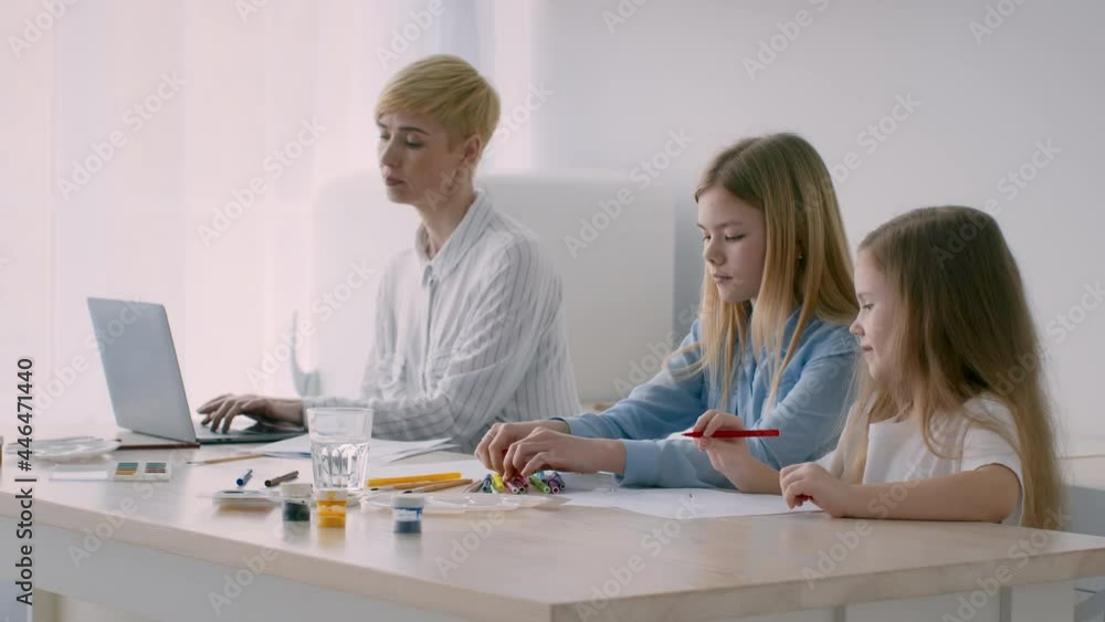 Freelancer Mother Working On Laptop While Daughters Drawing At Home Freelancer Mother Working On Laptop While Daughters Drawing At Home