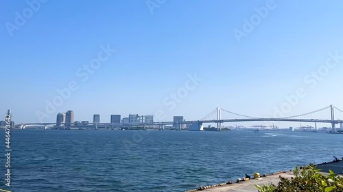 TAKESHIBA, TOKYO, JAPAN - APRIL 2021 : View of Takeshiba port (ferry terminal), Tokyo bay, ship and bridge at Odaiba area. Time lapse tracking shot in sunny day time. photo