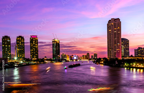 Bangkok Thailand Cityscape and Chao Phra Ya riverfront view on the sunset period with beautiful twilight and motion blurred of boat. For use as asian, Thailand night city scape background material. 