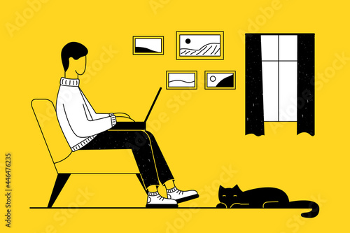 A man is sitting on the couch with a laptop at home and working, studying online remotely. A black domestic cat is lying on the floor. In the background there is a window and paintings.