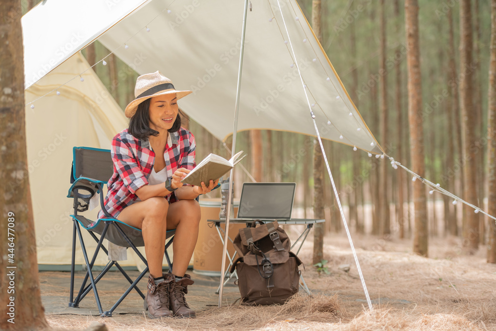Young woman tourist sitting near the tent and reading a book. people and lifestyles concept. travel and adventure theme. Female tourist portrait. Young woman tourist sitting near the tent and reading a book. people and lifestyles concept. travel and adventure theme. Female tourist portrait.