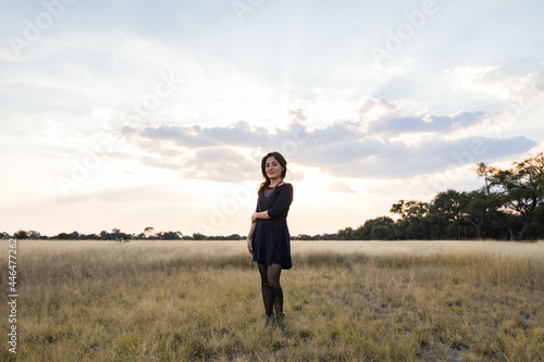 Young adult smiling Mexican woman standing in a dry grassy meadow looking at the camera