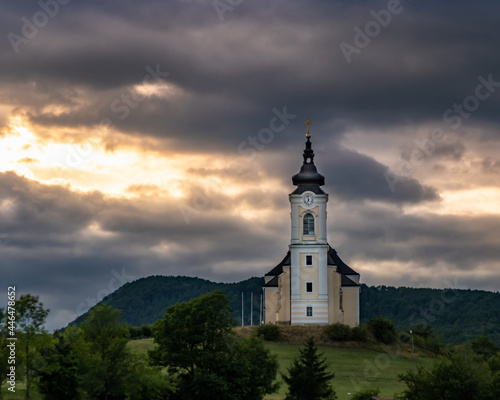 Der Sonnenuntergang zwischen den Gewitterwolken vor der Kulisse der Kirche