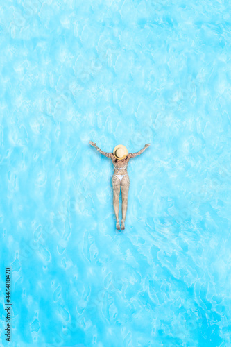 Young alone beautiful sports woman in bikini and hat is swimming in swimming pool. Aerial drone view from above. Vertical ratio  size