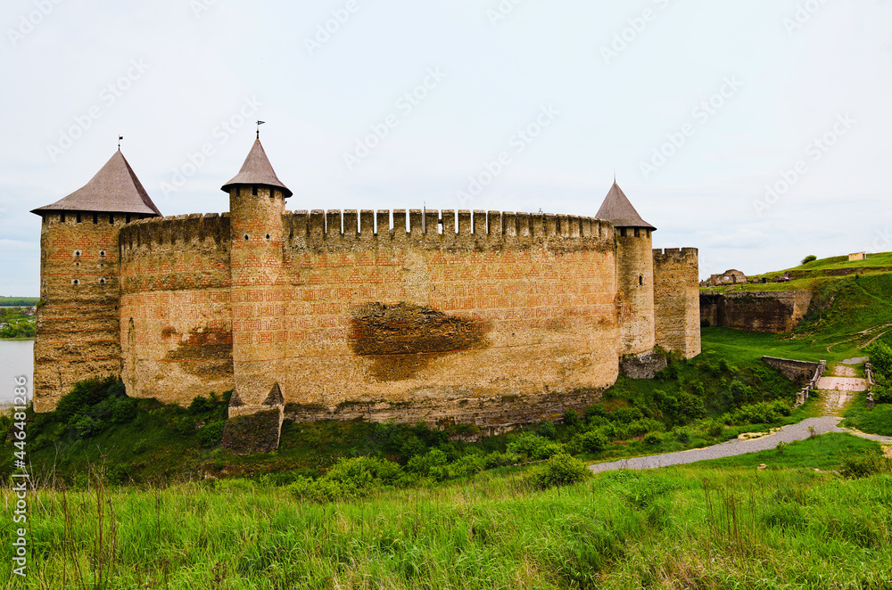 Wide angle landscape view of ancient fortress with high stone wall and towers. Blue sky background. Famous touristic place and romantic travel destination