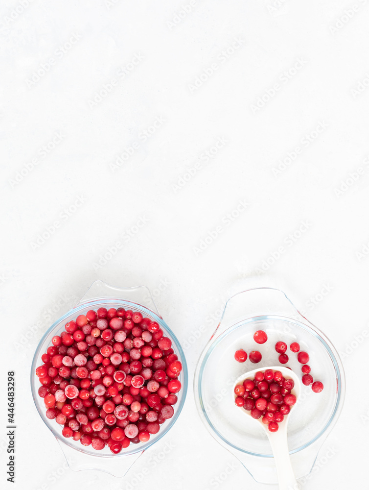 Frozen cranberries in a bowl on a white background. Frozen red berries. Vertical orientation. Copy space, top view, flat lay. Frozen cranberries in a bowl on a white background. Frozen red berries. Vertical orientation. Copy space, top view, flat lay.