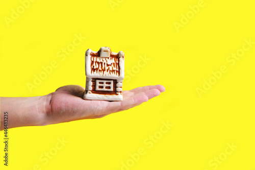 Toy house on palm of your hand on yellow background, mortgage sale or purchase of real estate, houses, apartments.