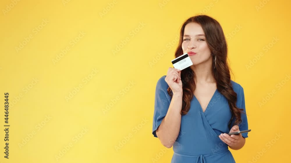 Banking app. Online transaction. Mobile payment. Satisfied female client using credit card phone for money transfer isolated on orange copy space background. Banking app. Online transaction. Mobile payment. Satisfied female client using credit card phone for money transfer isolated on orange copy space background.