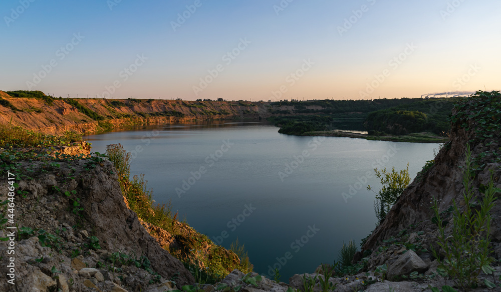 A beautiful lake in a deep abandoned quarry. Summer time, evening sunset. Scenery.
