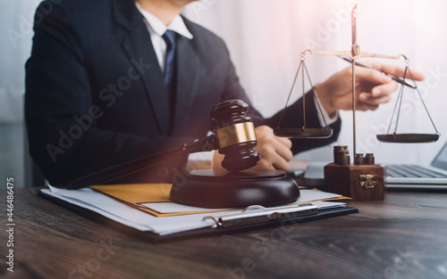 Justice and law concept.Male judge in a courtroom with the gavel, working with, computer and docking keyboard, eyeglasses, on table in morning light