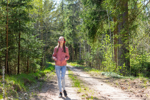 One lovely slim fit thin teen girl enjoying, listening to music in the forest while walking spring day forest or park.