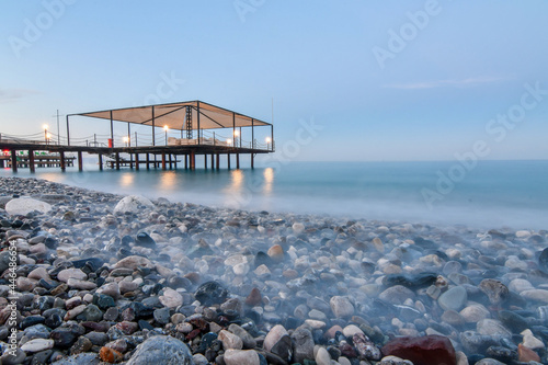 Close up of pier on the sea beach shot with long exposure at dusk time. Selective focus. © kyrychukvitaliy