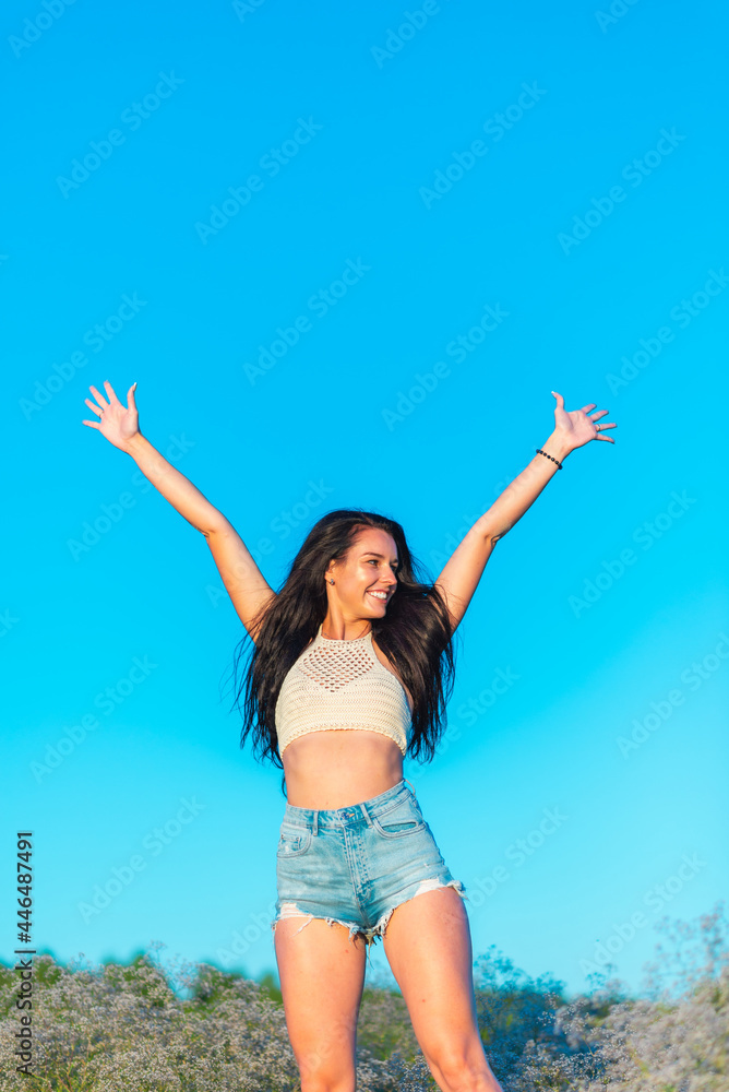 Joyful young girl raised his hands up and smiles. Happiness in lifestyle.woman raising her hands up in the blue air. Joyful young girl raised his hands up and smiles. Happiness in lifestyle.woman raising her hands up in the blue air.