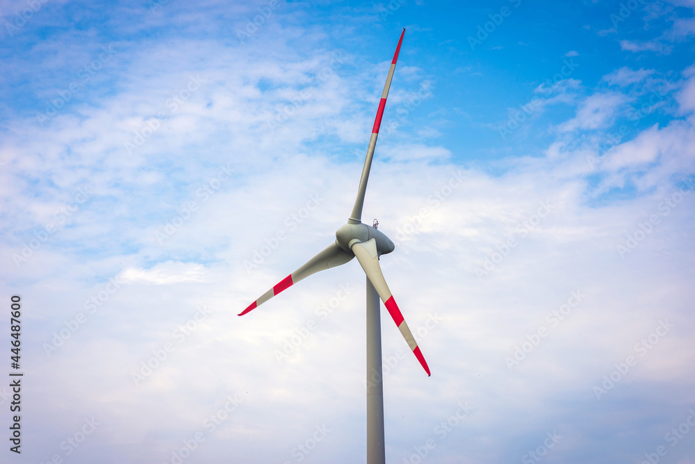 Single windmill generating electricity against blue sky.Beautiful wind turbine on blue sky clouds background.