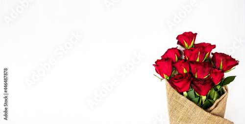 Red roses packed in burlap lie on a white background. Bouquet of flowers. Background and texture.