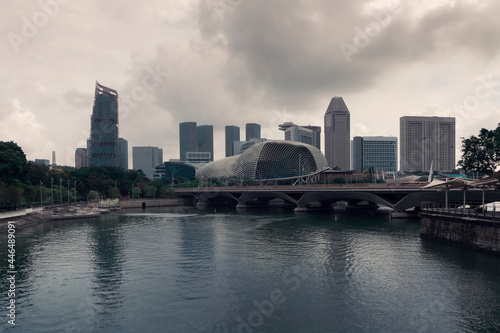 A pond and the Esplanade Theatres in front of skyscrapers against a sky by spring day